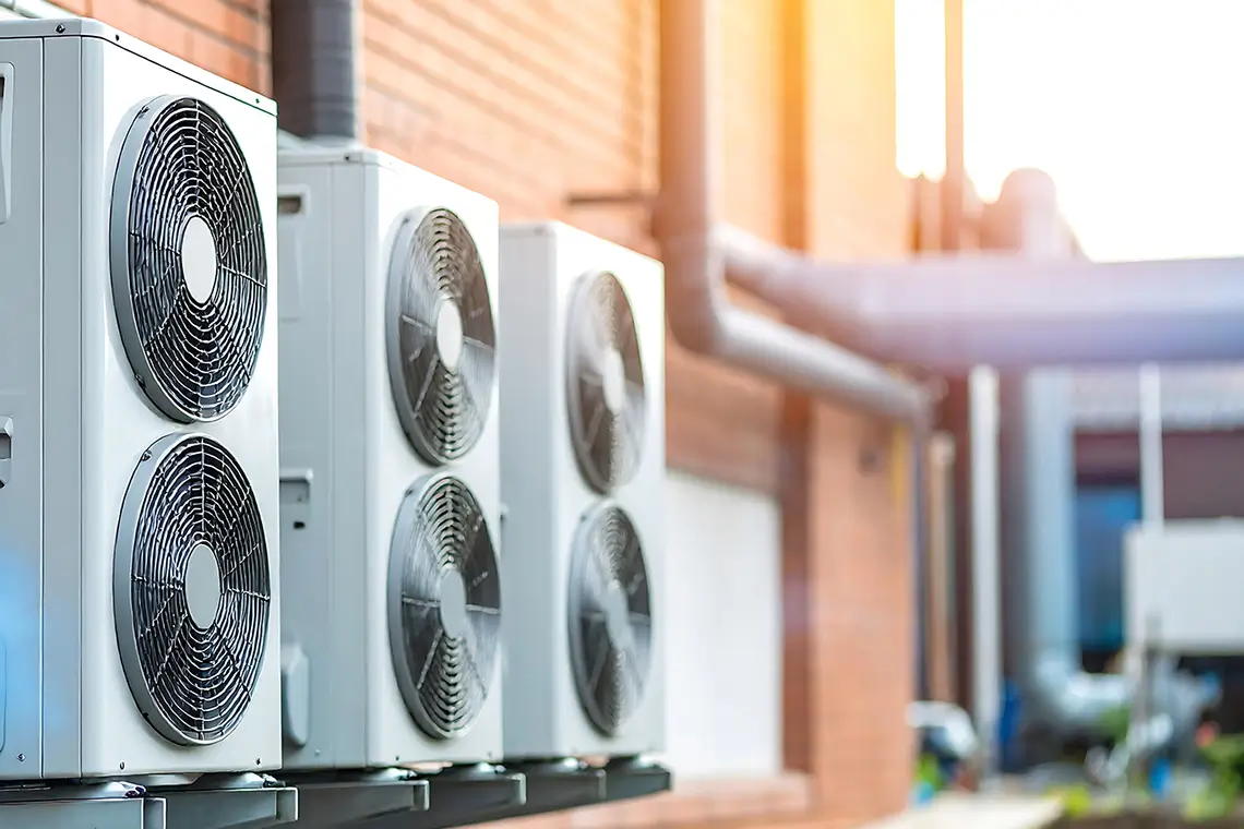 Mehrere Außengeräte einer Klimaanlage an der Außenwand eines Industriegebäudes