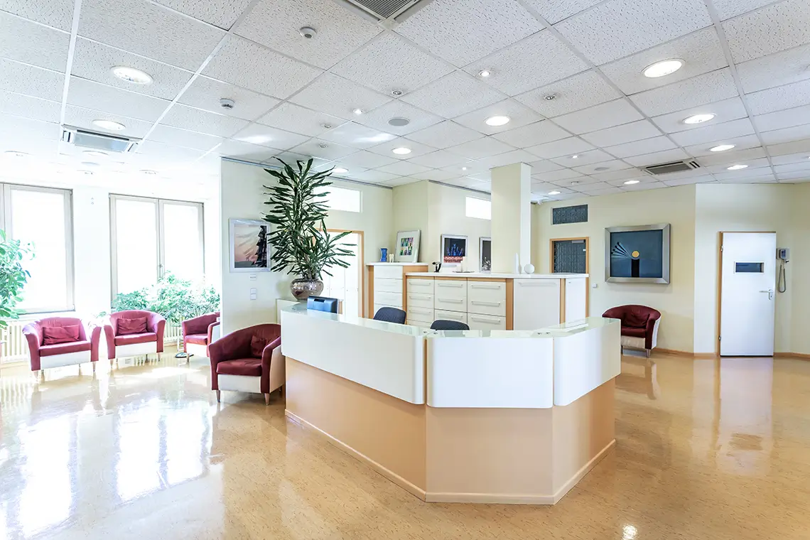 Helle Arztpraxis mit Empfangsbereich, Sitzgelegenheiten und Klimaanlage in der Decke