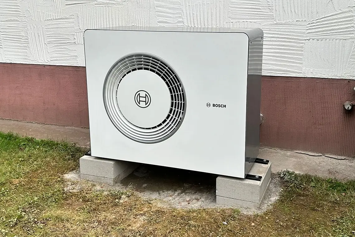 luft-wasser-waermepumpeLuft-Wasser-Wärmepumpe von Bosch steht auf Betonfundament an der Außenwand eines Hauses Luft-Wasser-Wärmepumpe von Bosch steht auf Betonfundament an der Außenwand eines Hauses