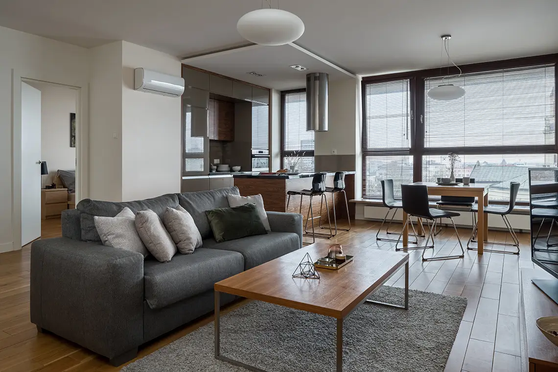 Offener Wohnbereich mit Küche, Esstisch, Sofa und Klimaanlage in einer modernen Wohnung.
