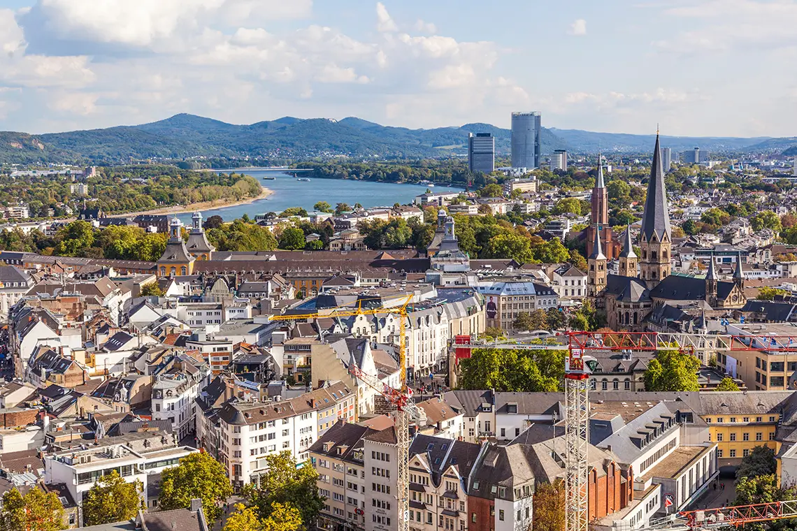 Panoramablick über Bonn mit Rhein, Altstadt, Kirchtürmen und dem modernen Post Tower im Hintergrund.