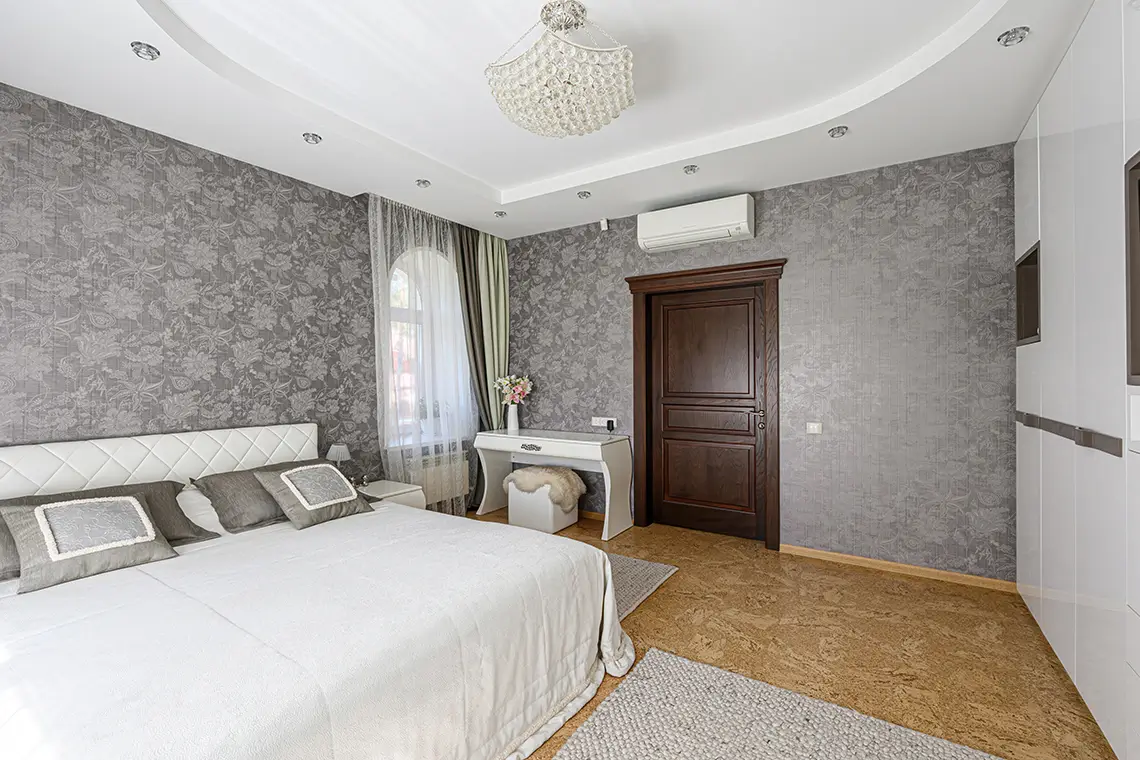 Elegantes Schlafzimmer mit Wandklimaanlage über der Tür und stilvoller Einrichtung Elegantes Schlafzimmer mit Wandklimaanlage über der Tür und stilvoller Einrichtung