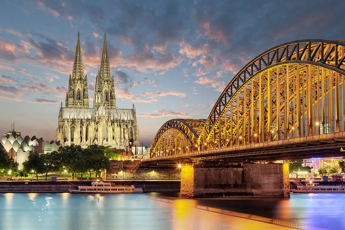 Kölner Dom und Hohenzollernbrücke am Abend mit beleuchteter Skyline am Rhein Kölner Dom und Hohenzollernbrücke am Abend mit beleuchteter Skyline am Rhein