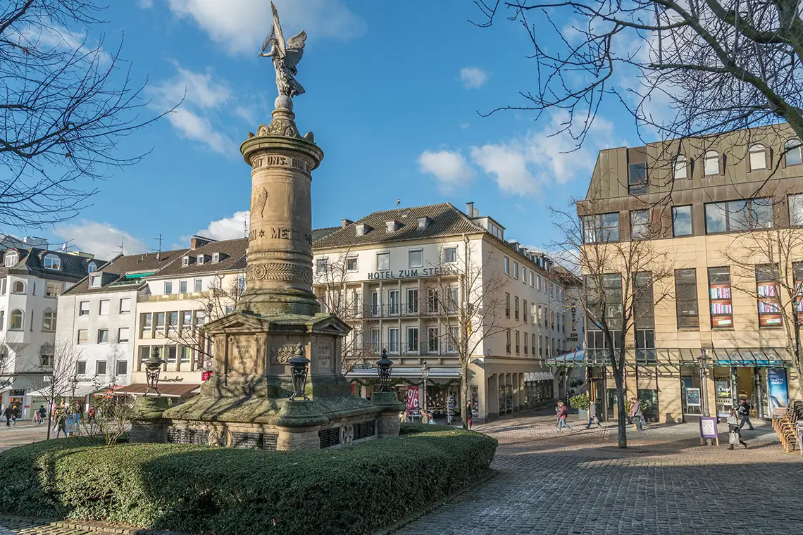 Historischer Marktplatz in Siegburg mit Denkmal, umliegenden Gebäuden und Passanten bei sonnigem Wetter Historischer Marktplatz in Siegburg mit Denkmal, umliegenden Gebäuden und Passanten bei sonnigem Wetter