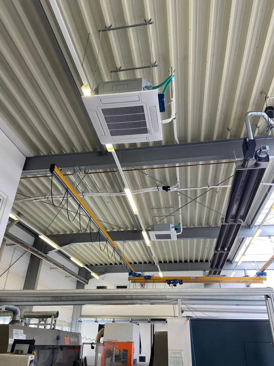 Deckenkassette einer Klimaanlage unter dem Hallendach einer Fabrikhalle in Troisdorf, darunter die CNC-Maschinen der Produktion.